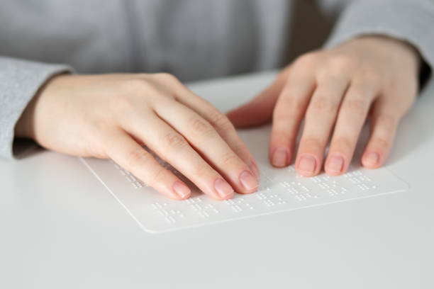 female hands touch the text for the blind braille stock photo