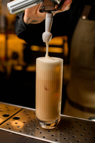 close-up of cocktail glass on the bar in which add whipped foam from creamer siphon - drink close up dairy product flowing imagens e fotografias de stock