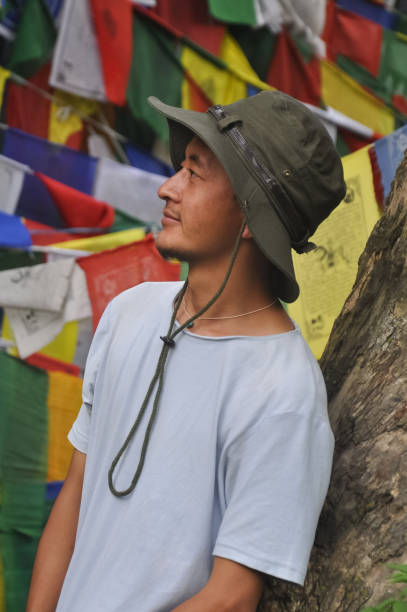 istock A happy asian young man looking sideways with touching hat on his head, posing against tibetan buddhist prayer flags 1359803119