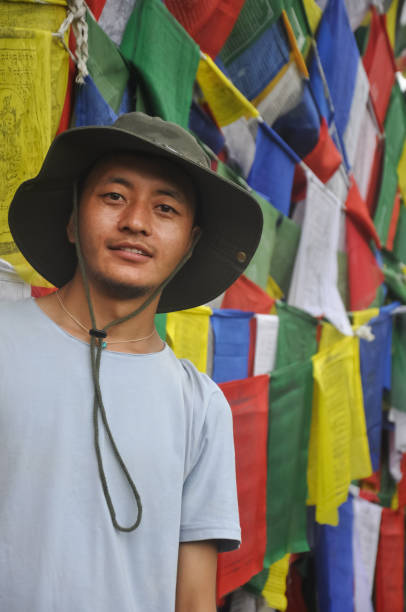 istock A Asian young guy looking at camera, standing against Buddhist prayer flags 1359803207