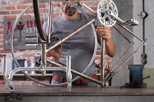 man repair the vintage bicycle in garage workshop on the workbench with tools, diy concept
