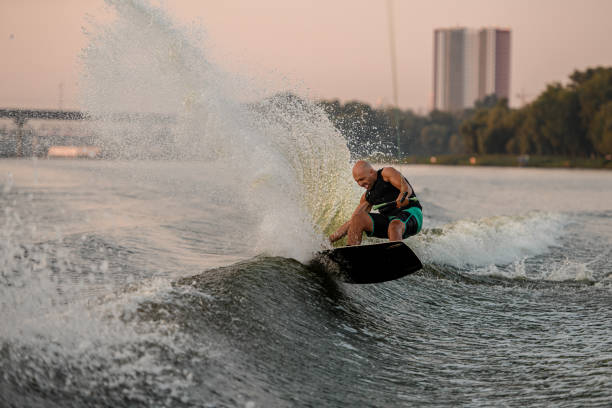 istock energy man trying to stand on splashing wave on a wakeboard 1359810471