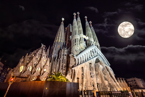 Low angle of La Sagrada Familia at night with a full moon