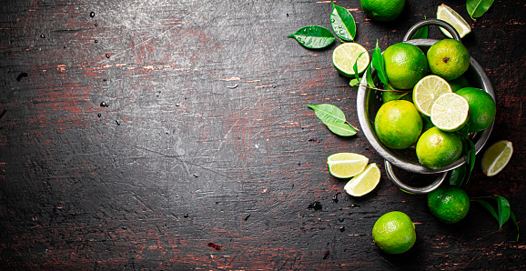 Fresh lime with leaves in a colander. On a rustic background. High quality photo