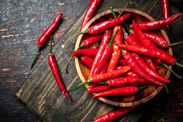 istock Red chili pepper pods on a cutting board. 1359813843
