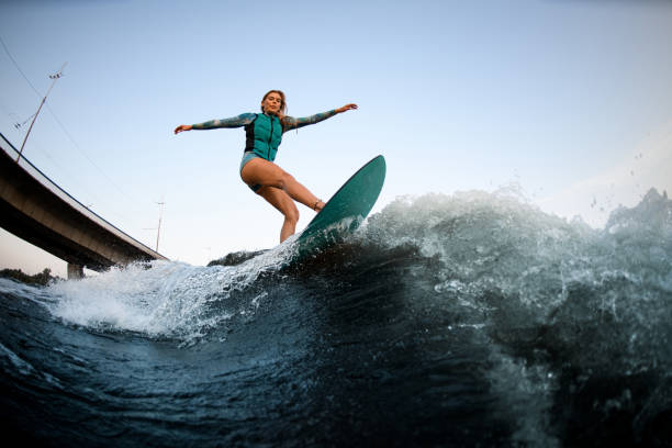istock attractive young woman wakesurfer actively balancing on surfboard along the river wave 1359814838