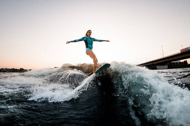 istock beautiful woman energetically balancing on great splashing wave on wakesurf. 1359814959