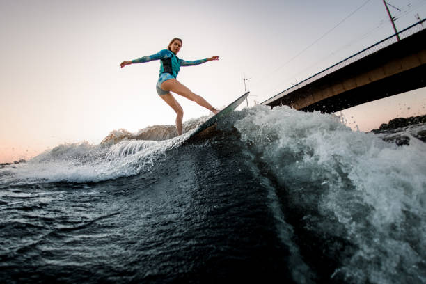 istock active woman energetically balancing on great splashing wave on wakesurf. 1359815882