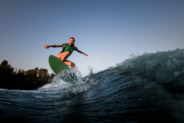 istock beautiful wet woman making trick with wakesurf on splashing wave. 1359816010