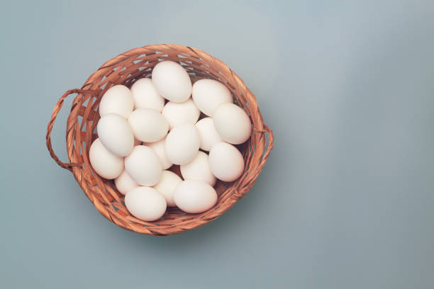 istock Wicker basket with white fresh chicken eggs on a gray background 1359816016