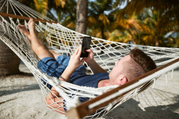 istock Man swinging in hammock and using smart phone 1359816050