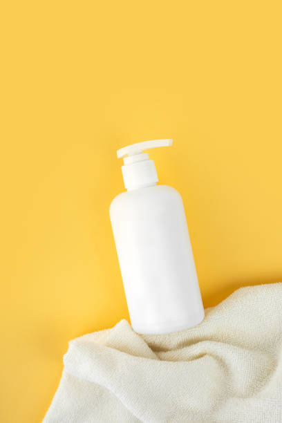 schiuma ipoallergenica naturale per bambini da bagno. bottiglia pompa in plastica bianca. cosmetici per bambini. bottiglie su uno sfondo giallo soleggiato e un asciugamano morbido. spazio di copia - pompa daria foto e immagini stock