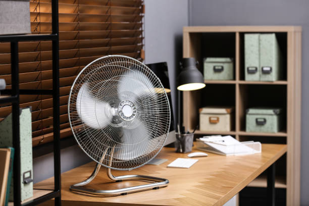 istock Modern electric fan on table in office 1359817094
