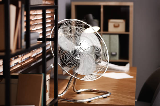 istock Modern electric fan on table in office 1359817223