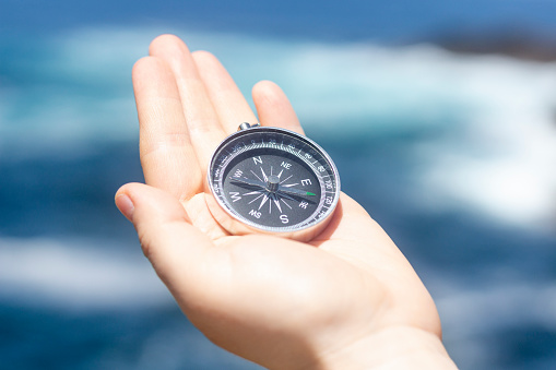 Close up, Hand holding a compass in front of the ocean. Travel, concepts