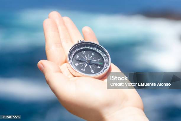 Hand Holding A Compass In Front Of The Ocean Stock Photo - Download Image Now - Human Hand, Navigational Compass, Adult