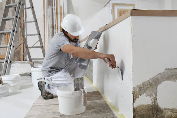 istock man plasterer construction worker at work, takes plaster from bucket and puts it on trowel to plastering the wall, wears helmet inside the building site of a house 1359817229