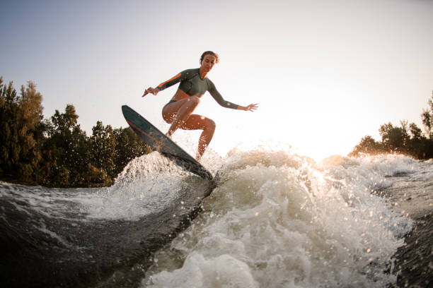 istock active fit woman making trick and jump with wakesurf over splashing wave. 1359817836