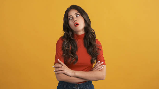 Casual bored girl in red top with hands crossed tiredly posing on camera over yellow background. Not interested expression Casual bored brunette girl in red top with hands crossed tiredly posing on camera over yellow background. Not interested expression rolling eyes stock pictures, royalty-free photos & images