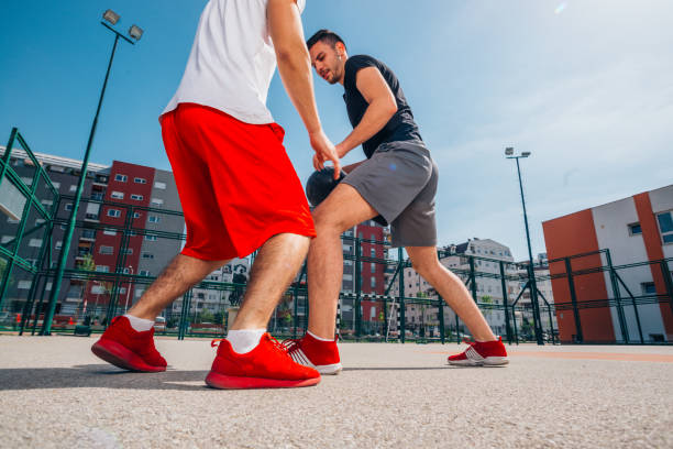 deux athlètes jouant un match de basket-ball de rue sur un terrain de basket-ball urbain (se poussant, se tirant l’un l’autre et tirant pour trois). - building block photos et images de collection