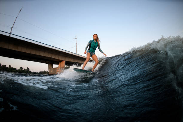istock active woman wakesurfer riding down the great splashing river wave. 1359818401