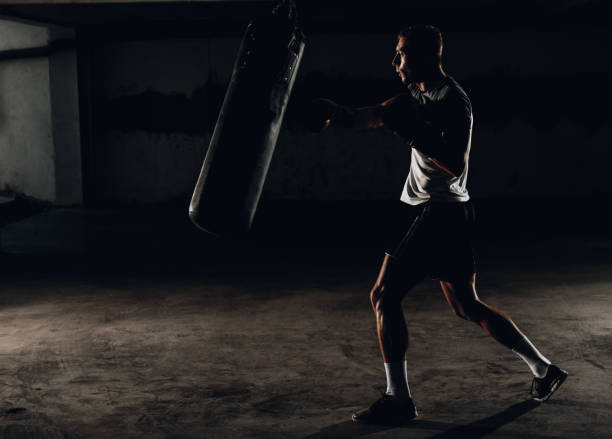 istock Fit professional boxing man kicking at punching bag 1359818578