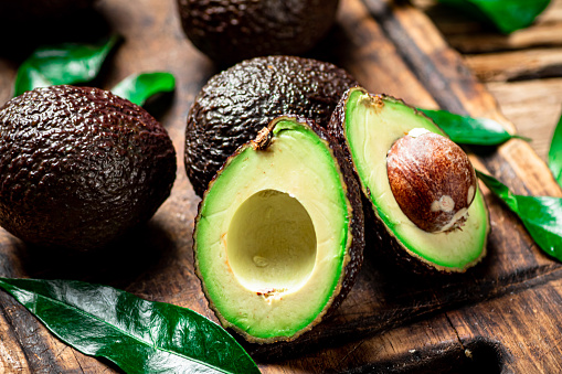 Halves of fresh avocado on a cutting board. On a wooden background. High quality photo