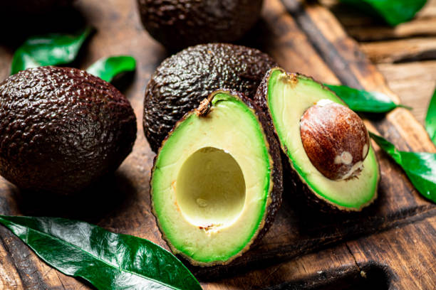 Halves of fresh avocado on a cutting board. Halves of fresh avocado on a cutting board. On a wooden background. High quality photo ripe stock pictures, royalty-free photos & images