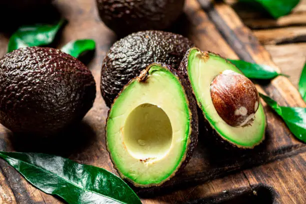 Photo of Halves of fresh avocado on a cutting board.