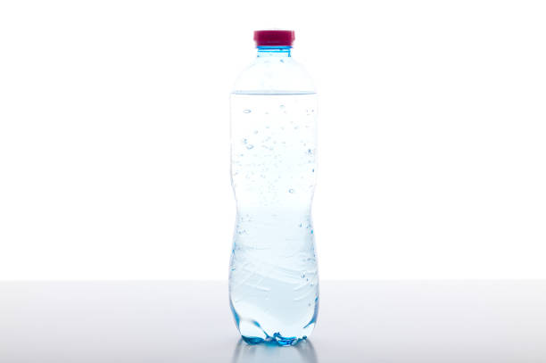 una botella de agua con gas sobre la mesa. botella de plástico con agua sobre fondo blanco. - backwash fotografías e imágenes de stock