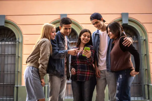 Photo of Teenager friends using the mobile phone outdoors