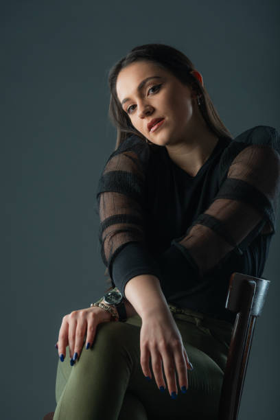 istock Attractive brunette model sitting on a old chair posing and looking at camera on grey background 1359821749