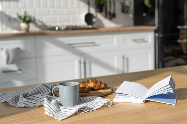 istock Book, croissant and cup of coffee on table in kitchen 1359821995