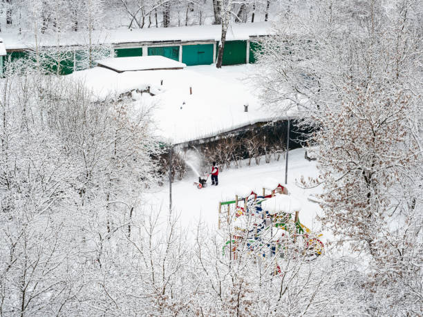 istock janitor cleaning path from snow in city garden 1359822878