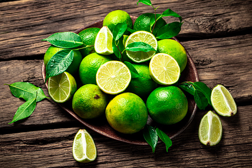 Juicy lime with leaves on a plate. On a wooden background. High quality photo