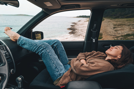 woman resting in car parked at sea beach. summer vacation