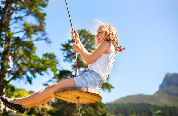 夏にブランコに座っている笑う小さな女の子 - swing child swinging front or back yard ストックフォトと画像