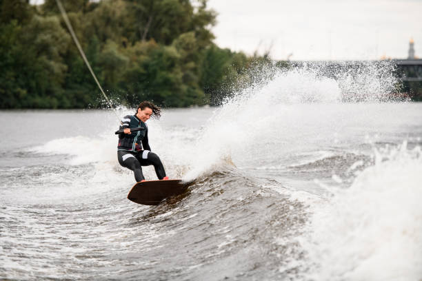 istock active female wakeboarder balances on splashing wave on board holding rope with her hand 1359826105