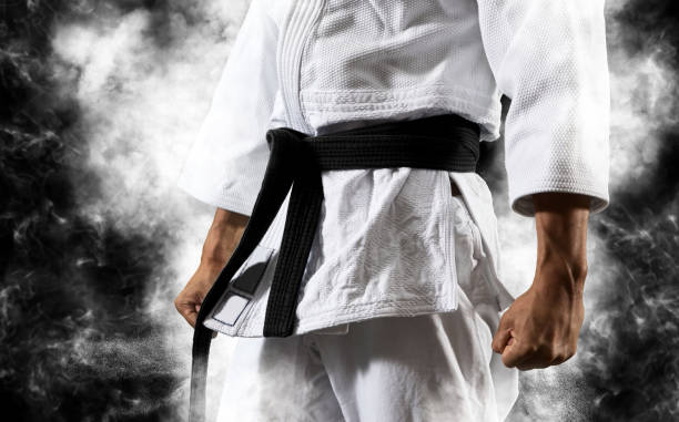 Guy poses in white kimono with black belt.  Japanese judo and sports concept