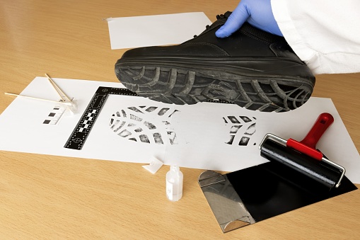 A scientific police investigator, CSI, in the laboratory, with ink, takes samples of the shoe prints