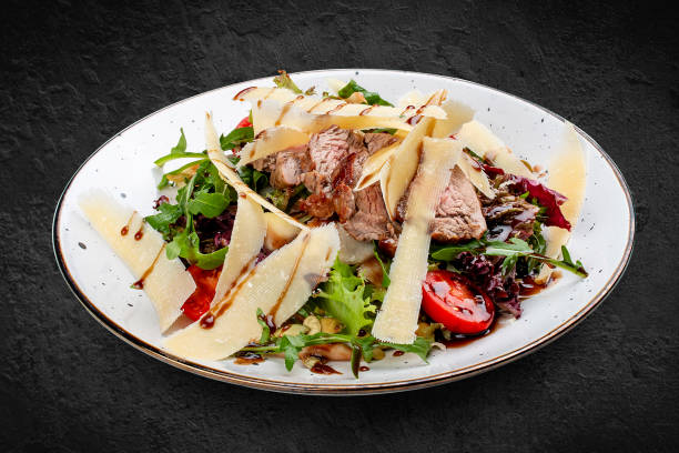 istock Veal and pear salad with olive-balsamic dressing. Isolated on a black background. 1359829272