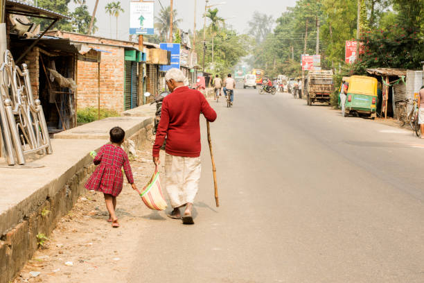 mała dziewczynka próbuje pomóc starcowi nosić torbę. selektywne ustawianie ostrości. - india mountain child people zdjęcia i obrazy z banku zdjęć
