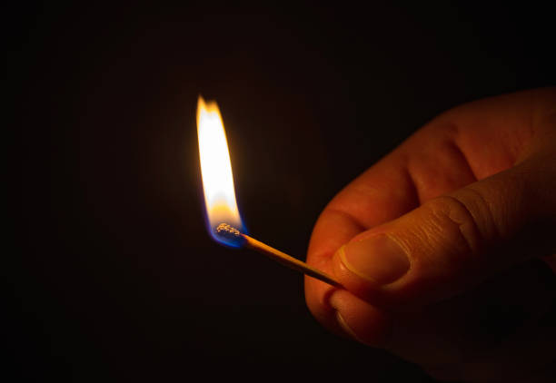 istock Lit matchstick in dark home. 1359833489