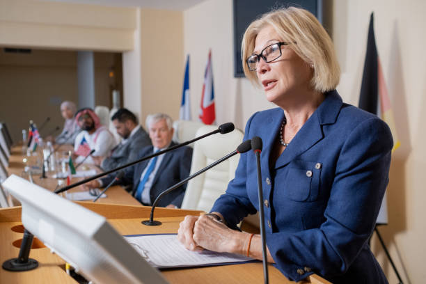 istock Mature blond delegate in formalwear speaking in microphone 1359833735