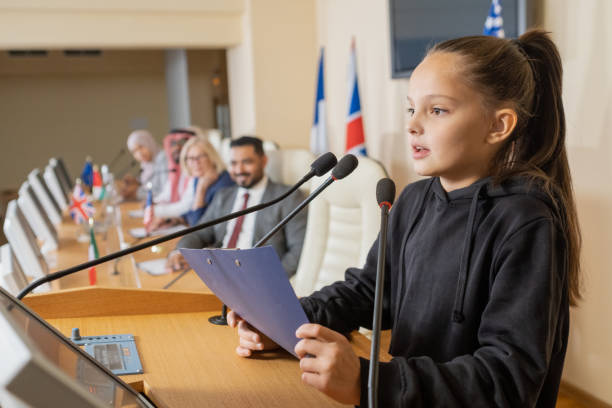 cute schoolgirl with clipboard making report by tribune - press conference public speaker politician speech imagens e fotografias de stock