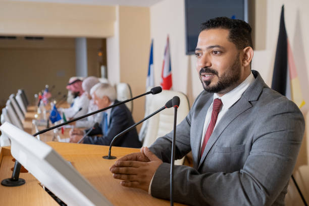 istock Confident politician speaking in microphone by tribune 1359833760