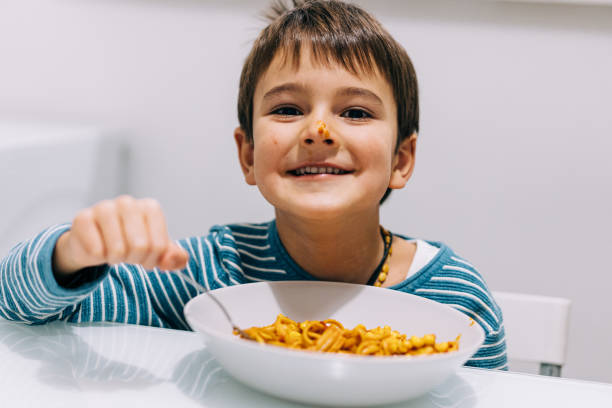 istock Cute boy eating spaghetti for dinner and making a mess. 1359835158