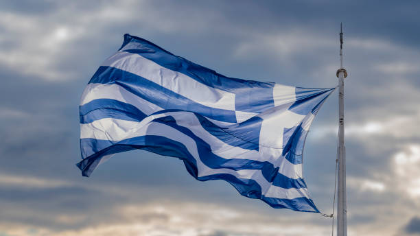 istock The Greek flag against dramatic beautiful sunset and clouds, moving with the wind . 1359839101