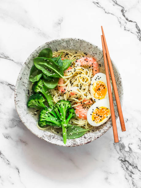 istock Asian style lunch - ramen egg noodles with shrimp, broccoli, spinach and boiled egg on a light background, top view 1359839734
