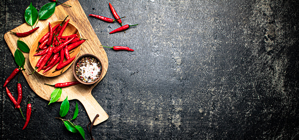 Pods of hot chili peppers on a cutting board. On a black background. High quality photo